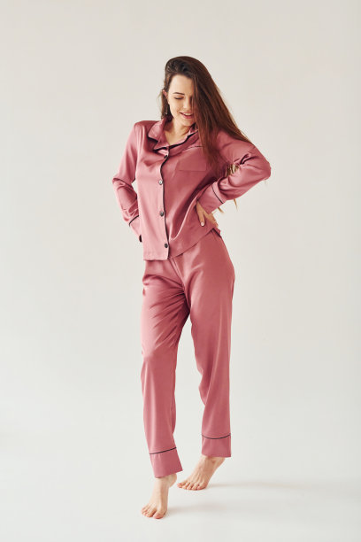 穿着睡衣的快乐年轻女子站在室内，背景是工作室的白色图片下载