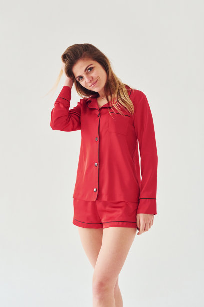 白天，穿着红色睡衣的快乐年轻女子站在室内，以白色为背景图片下载