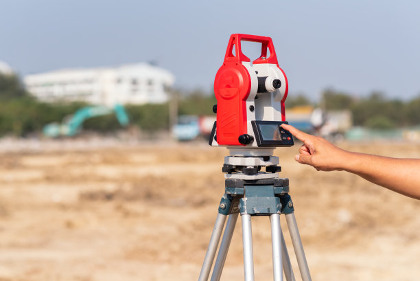 经纬仪或设备总定位站在具有工程机械背景的道路或建筑物施工现场图片下载