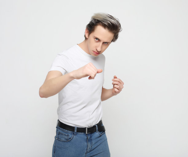 年轻好斗的男子穿着白色的t恤，露出拳头，看着镜头图片下载