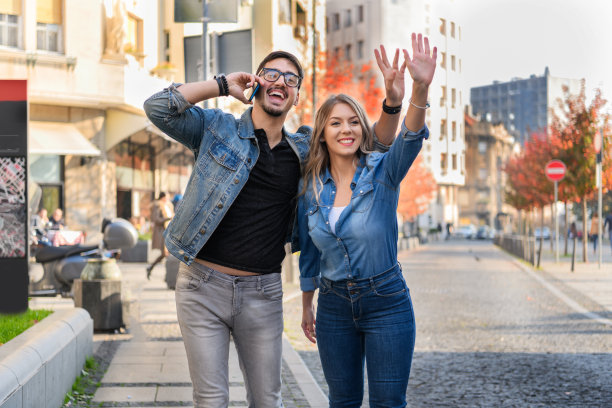 一对年轻夫妇正站在城市街道的路边，试图赶上一辆交通工具。图片下载