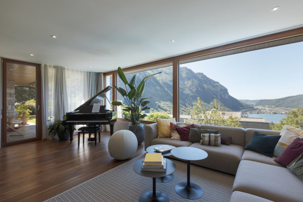 客厅里有大的浅色沙发和许多靠垫，还有一架黑色钢琴。俯瞰山谷的大窗户图片下载