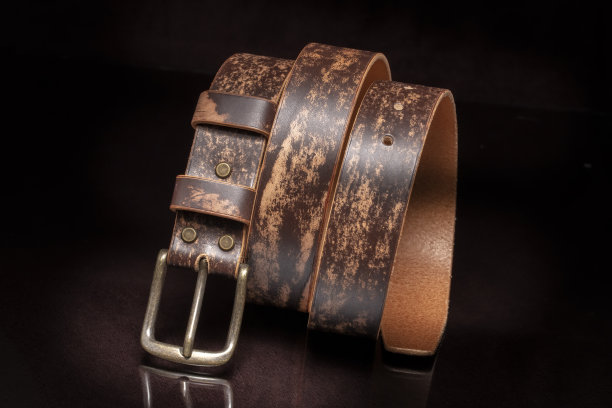 棕色皮带与磨损和金属扣在黑暗的背景。图片下载