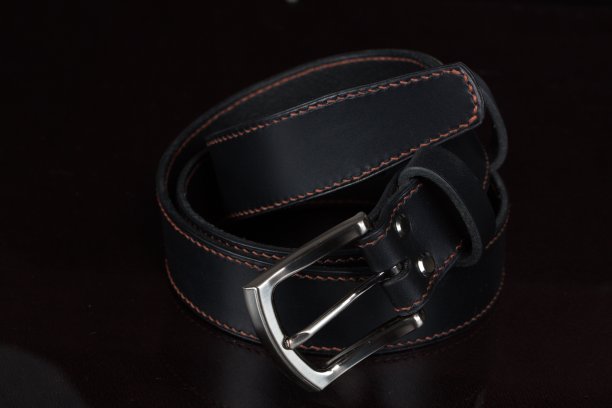 黑色皮带与金属扣上黑色背景特写。图片下载
