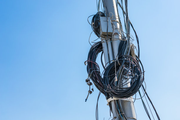 在天空的背景下，许多不同的电线缠绕在柱子上图片下载