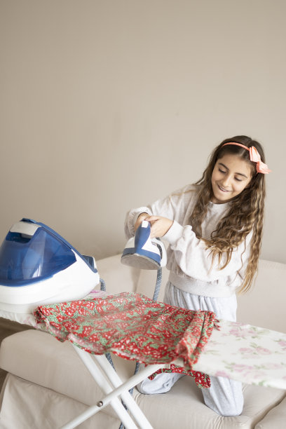 可爱的女孩享受着熨斗上的熨衣板图片下载