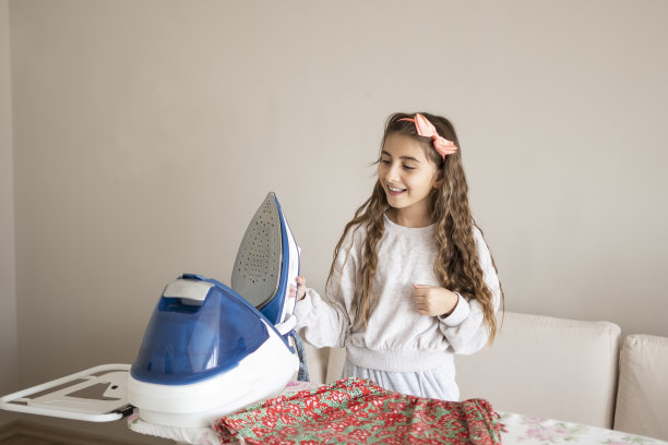 可爱的女孩享受着熨斗上的熨衣板图片下载