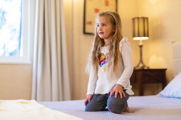 在家庭照片系列中，学龄前女性在床上冒险蹦跳图片下载