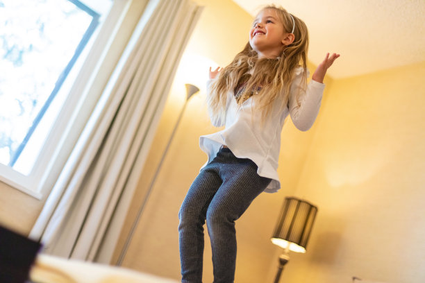 在家庭照片系列中，学龄前女性在床上冒险蹦跳图片下载