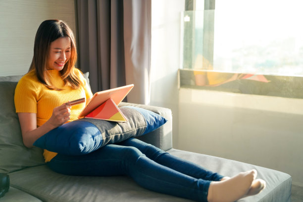 用信用卡在平板电脑上网购的亚洲女性图片下载