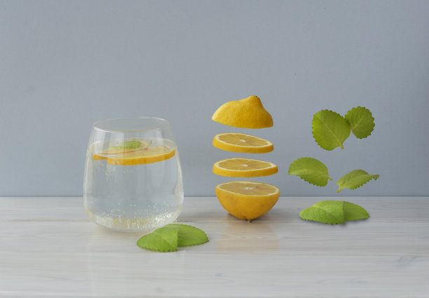 柠檬片和薄荷叶悬浮在一杯水附近的灯光背景，copyspace。图片下载