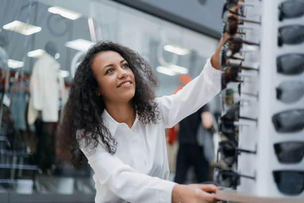 一位年轻女子在挑选镜框漂亮的太阳镜图片下载