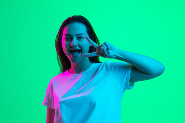 欢快的年轻美丽的女孩的肖像，女模特孤立在明亮的绿色背景霓虹灯。图片下载