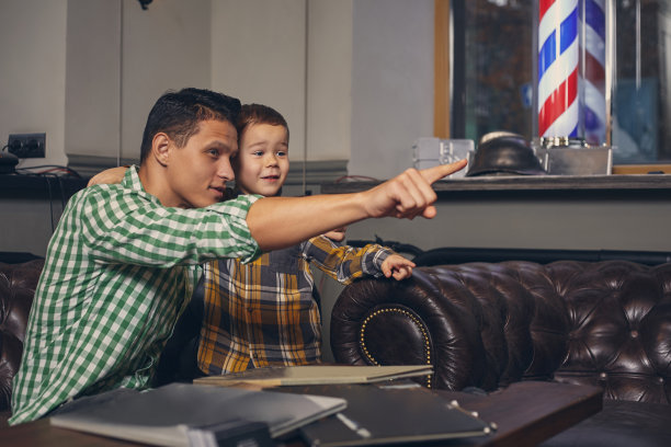 年轻的父亲和他时髦的小儿子在候车室里的理发店里图片下载