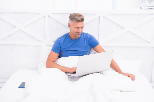 网上购物。在线交流。居家办公检查消息。睡在床上的成熟男人。商人与计算机。潮人在笔记本电脑上工作。卧室变成了新的办公室。远程工作图片下载