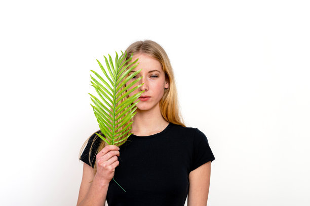 一个漂亮的年轻女性的肖像与蕨枝在她的脸，孤立在白色的背景图片下载