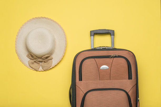 俯视图的一个女人的帽子和手提箱与一个处理在一个黄色的背景。平的。图片下载