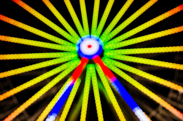 游乐园晚上的图像散焦和模糊。夜景下的摩天轮和云霄飞车。公园骑图片下载