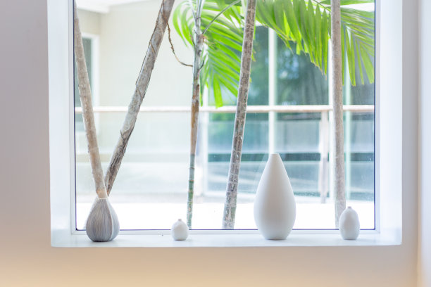 窗边白色现代陶瓷花瓶收藏。房间里中午的光线。柔软的家居装饰，在白色的墙壁背景，复制空间图片下载