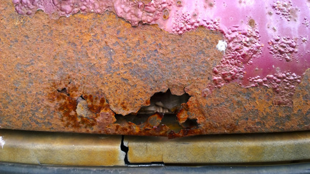 旧红色轿车的金属片腐蚀。生锈的混乱的表面。被损坏的垃圾，肮脏的纹理从道路盐。生锈的背景。保护汽车概念。外套。副本的空间。油漆和修复。洞。图片下载