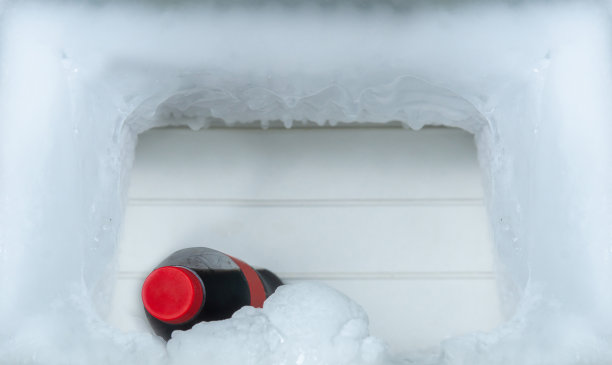 一瓶可乐饮料，冰箱的冰柜上有冰块，文字拷贝空间。图片下载