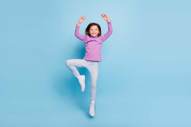 甜美漂亮的学校女孩的照片穿紫色高领跳芭蕾舞微笑孤立的蓝色背景图片下载