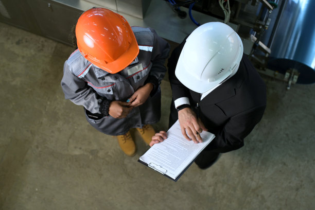 戴着橙色和白色头盔的工人和老板在谈论生产中的工作图片下载