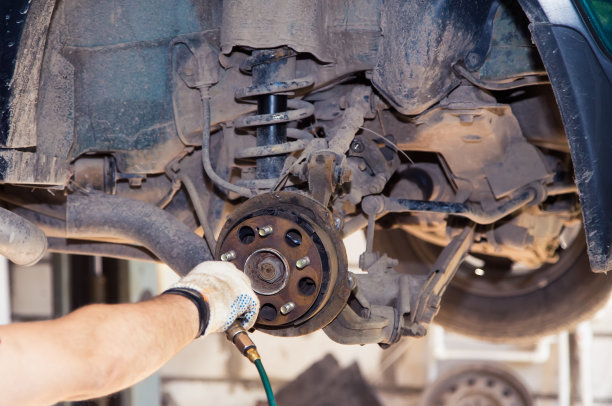 一只戴着手套的手向一辆旧车的后刹车片吹压缩空气图片下载