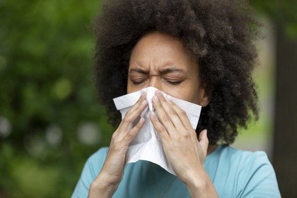 患有鼻窦炎的非裔美国妇女正在公园里擤鼻子。图片下载