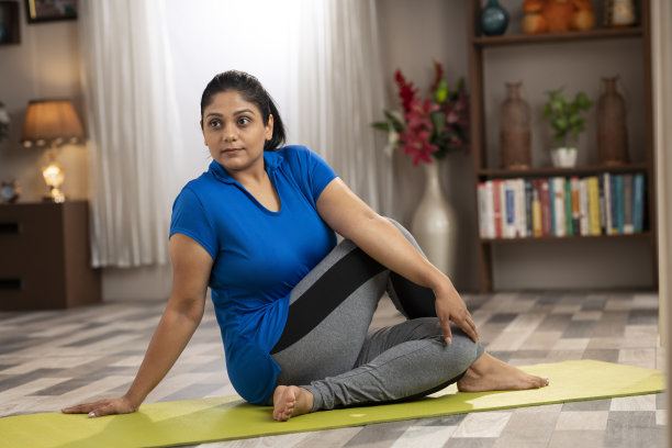一个中年妇女在家里做瑜伽和伸展手臂的照片图片下载