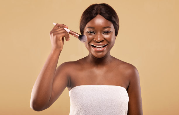 漂亮的黑人女人拿着化妆刷和微笑在相机的特写图片下载