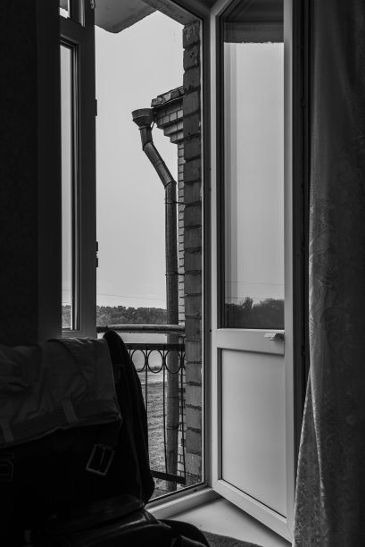 从房间到开放式阳台，后面是阳台栏杆、水管、多云的天空、森林和河流。图片下载