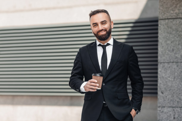 西装革面的帅气商人站在办公中心附近，休息的时候喝咖啡图片下载
