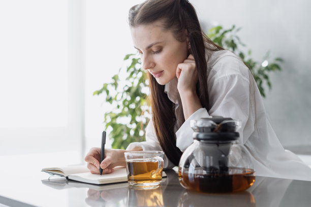 年轻女人一边喝茶一边记录想法图片下载