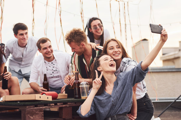 制作照片。美味的披萨。一群穿着便服的年轻人在白天一起在屋顶聚会图片下载