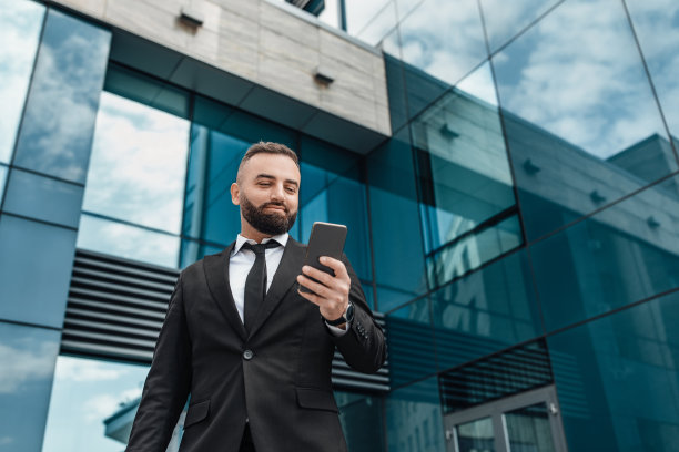 商业生活方式的概念。英俊的商人使用智能手机，站在办公大楼，复印空间图片下载
