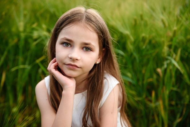 田野里的漂亮姑娘。一片绿色的麦田。一个孩子的肖像。一个年轻女孩的长发。图片下载