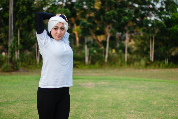 戴着头巾穿着运动服做瑜伽和伸展运动的可爱女人。穆斯林年轻妇女早上在户外训练。图片下载