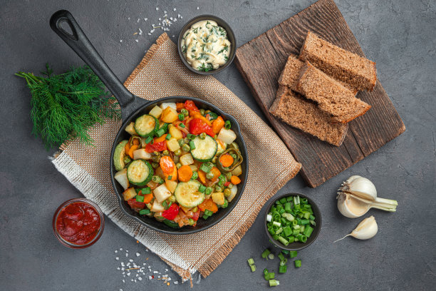 健康的午餐，有蔬菜炖菜，新鲜的香草和黑麦面包在灰棕色的背景图片下载