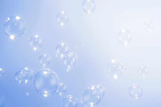 美丽透明的肥皂泡漂浮在蓝色的背景。图片下载