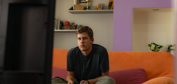 年轻人坐在家里，在客厅里，玩电子游戏，享受他的空闲时间。图片下载