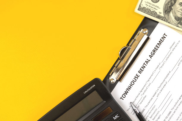 联排房屋租赁协议表格。办公室的桌面上有计算器，笔和钱。俯视图照片和复制空间图片下载