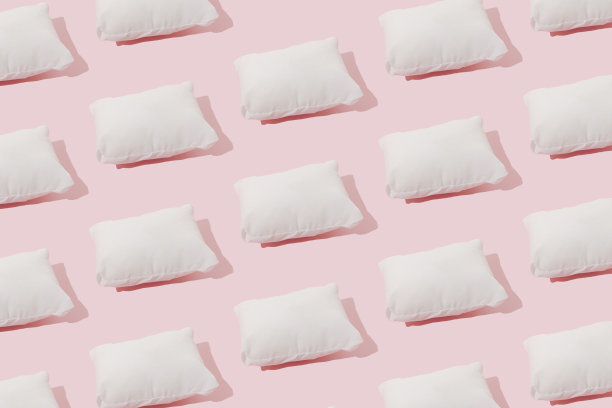 粉色背景上的白色枕头。最小的模式。图片下载