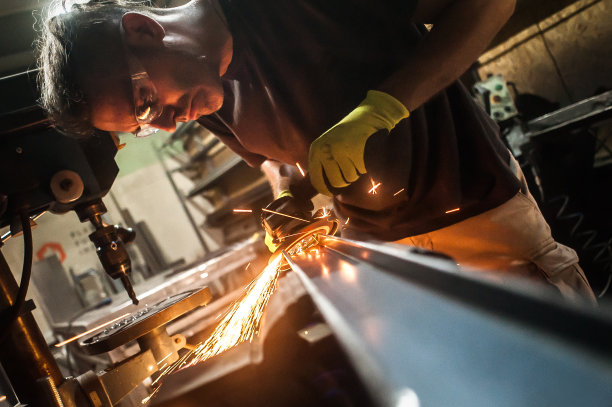 工厂内工匠用电动磨床工具打磨钢结构图片下载