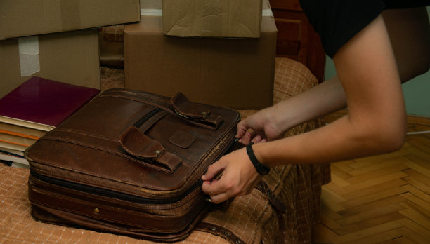 一个学生搬进了他的宿舍，开始了他的学生生活，拿着箱子进入他的房间，整理他的东西。图片下载