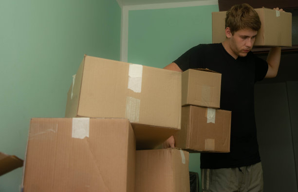 一个学生搬进了他的宿舍，开始了他的学生生活，拿着箱子进入他的房间，整理他的东西。图片下载