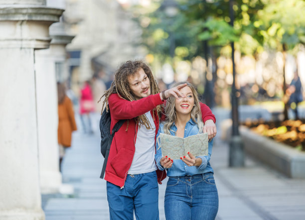 一对年轻的快乐旅行者正在城市中行走，并使用地图探索风景。图片下载