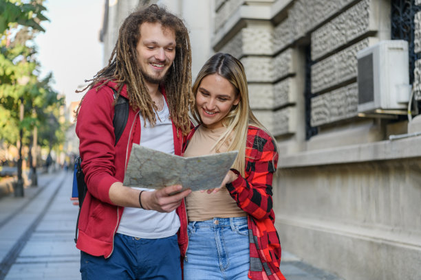 一个年轻人和他的女朋友带着旅游地图在市区散步。图片下载
