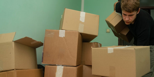 一个学生搬进了他的宿舍，开始了他的学生生活，拿着箱子进入他的房间，整理他的东西。图片下载