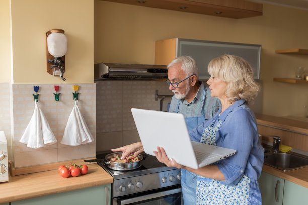 一对老夫妇正在家中享用美味佳肴，并在网上查找食谱。图片下载